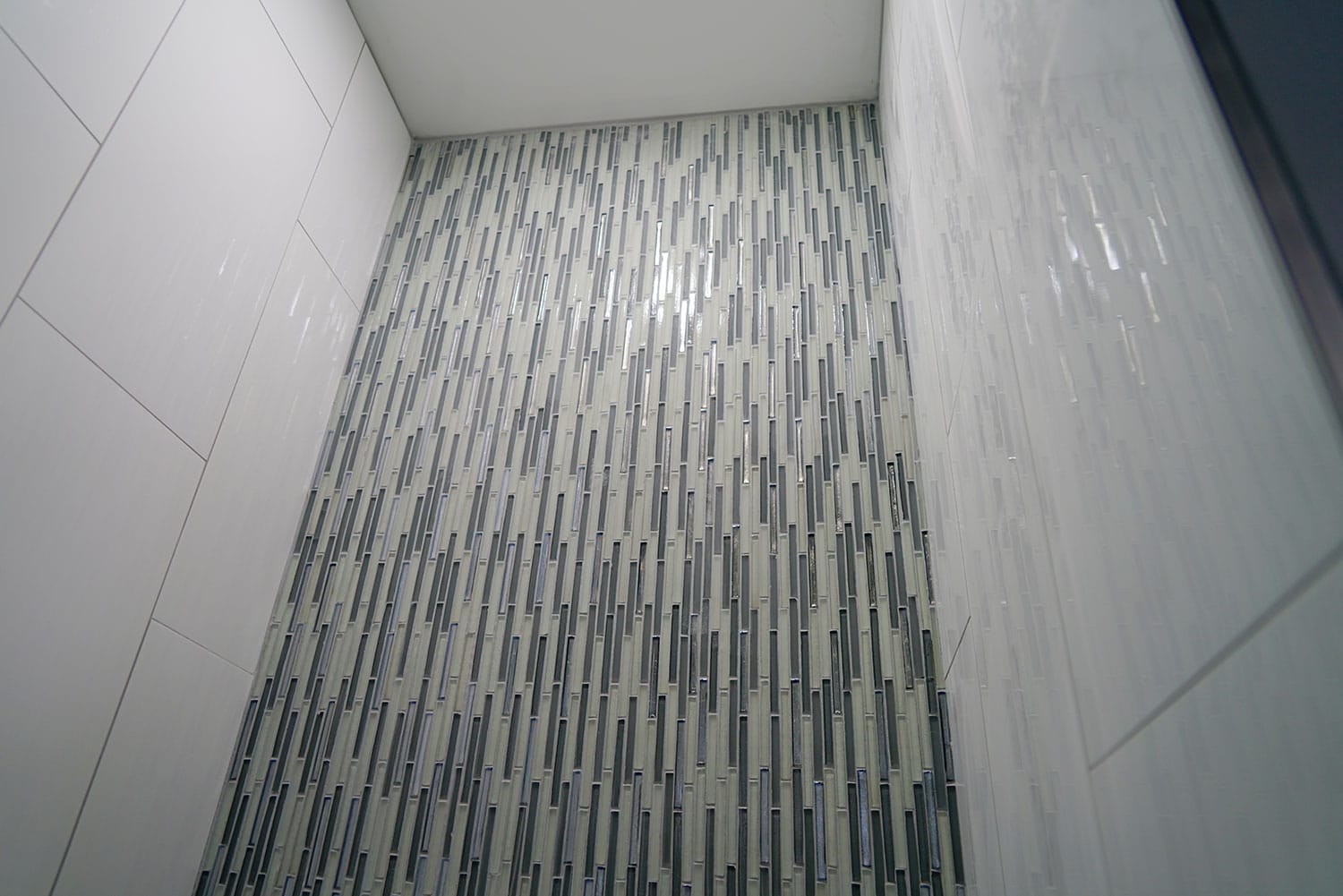 Shower walls with modern glass mosaic tiles.