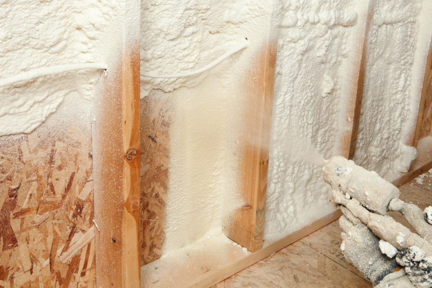 Spray foam insulation being installed with sprayer in an unfinished wall.